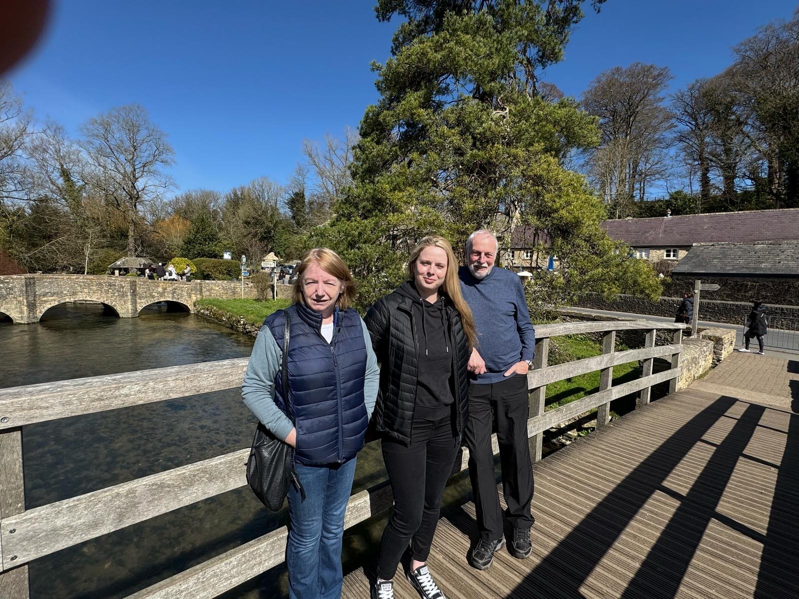 Family standing together beside a river and bridge