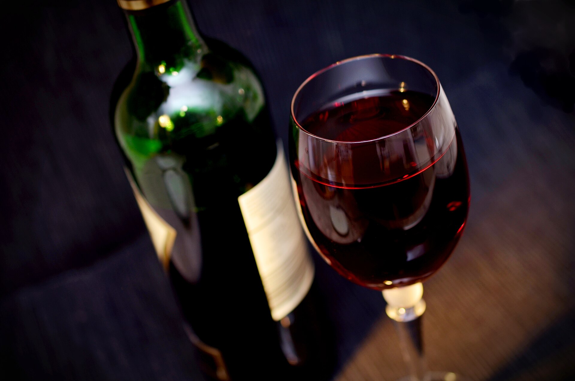 A bottle and glass of red wine on a wooden table